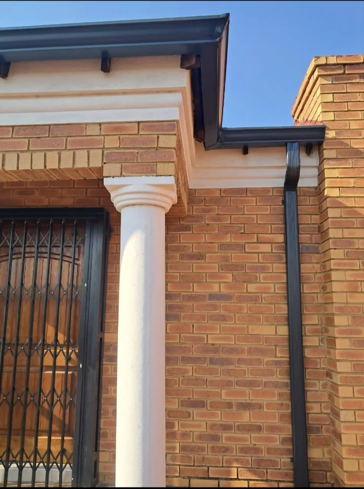 Dark downpipe and seamless gutters fitted to a brick house